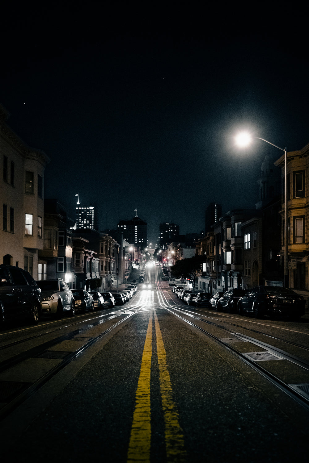 Empty city street at night with cable car tracks and glowing streetlights